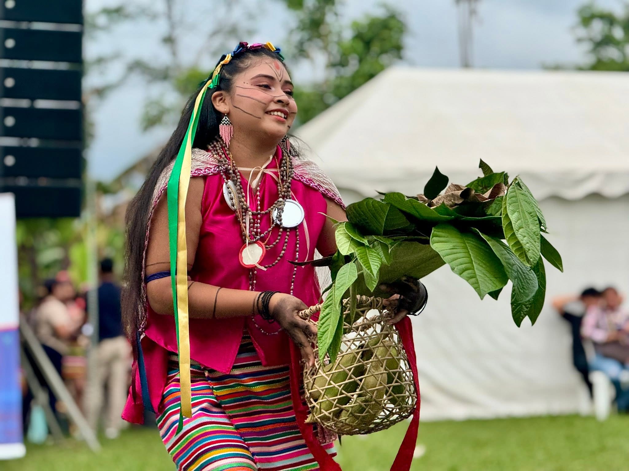Mujer tsáchila con vestimenta tradicional llevando una canasta de hojas y frutos